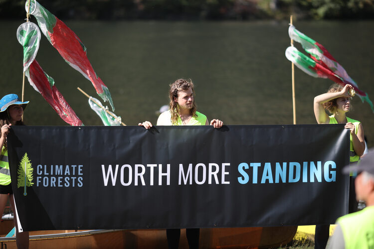 activists stand behind a sign reading &ldquo;Worth More Standing&rdquo;