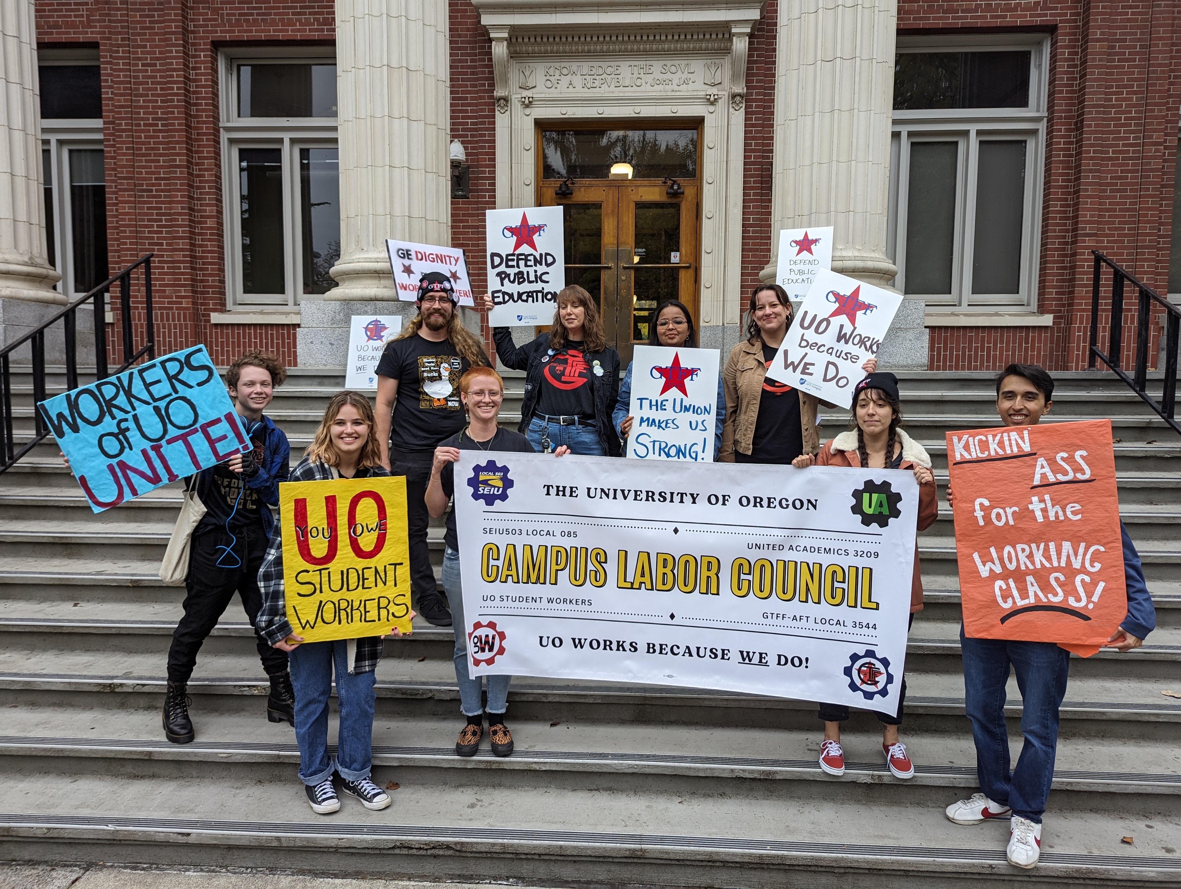 Organizers from UOSW and GTFF gathered in front of Johnson Hall, holding picket signs and a banner for the Campus Labor Council, the coalition of the four unions representing workers on campus. from UOSW and GTFF gathered in front of Johnson Hall, holding picket signs and a banner for the Campus Labor Council, the coalition of the four unions representing workers on campus.