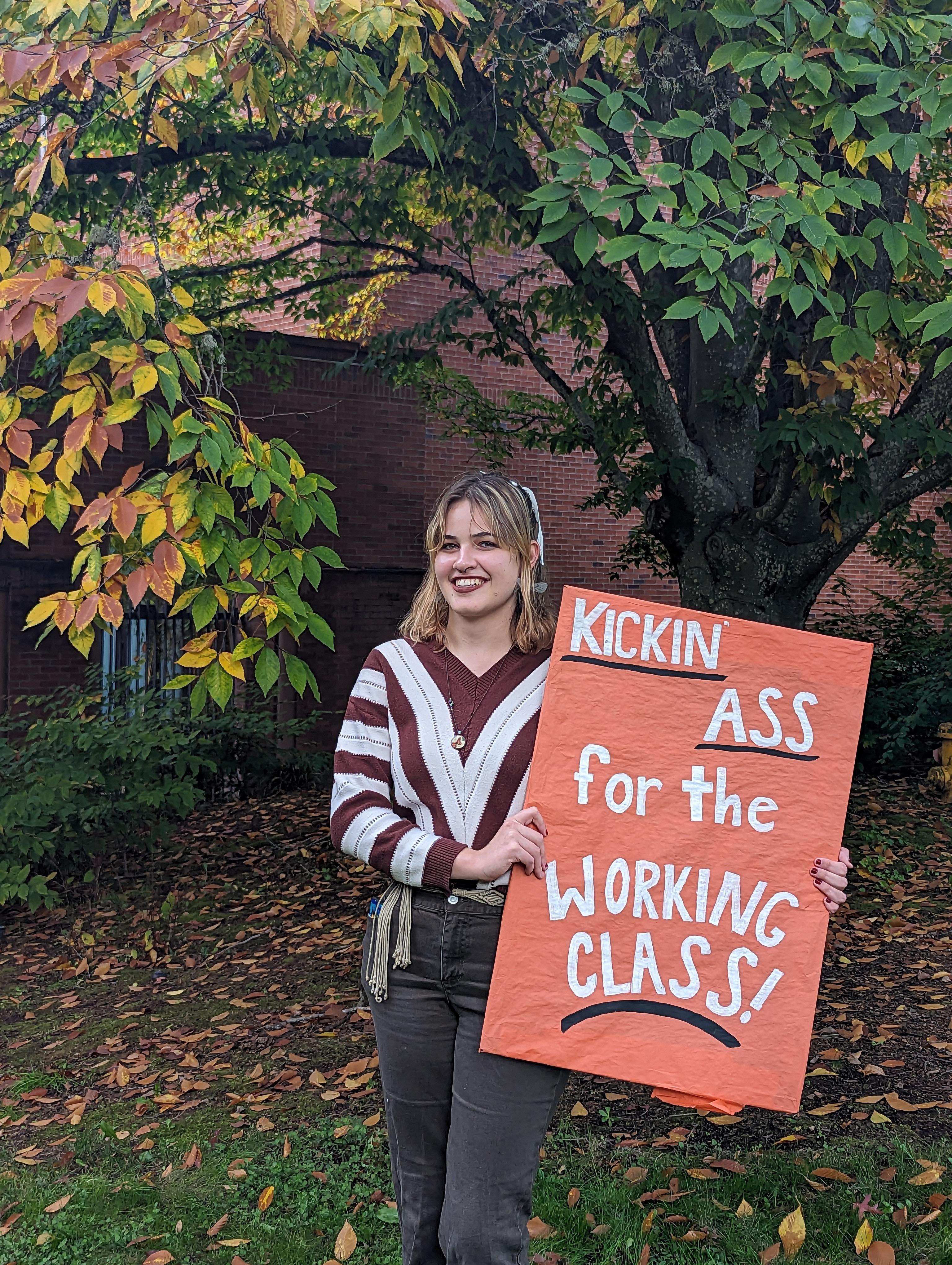Carolyn Roderique, UOSW organizer and Resident Assistant holds a sign &ldquo;kickin ass for the working class!&rdquo;