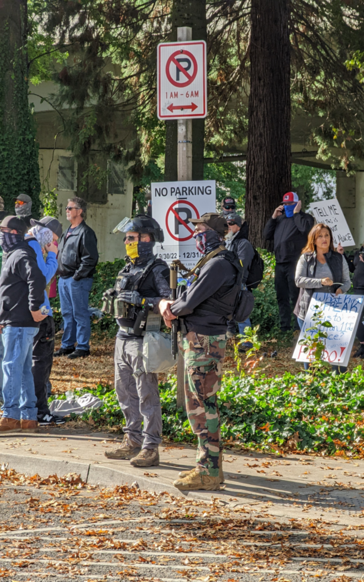 Two individuals among right-wing crowd carrying weapons.