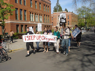 A dozen students march with signs. A large banner reads “Step Up, Oregon!”
